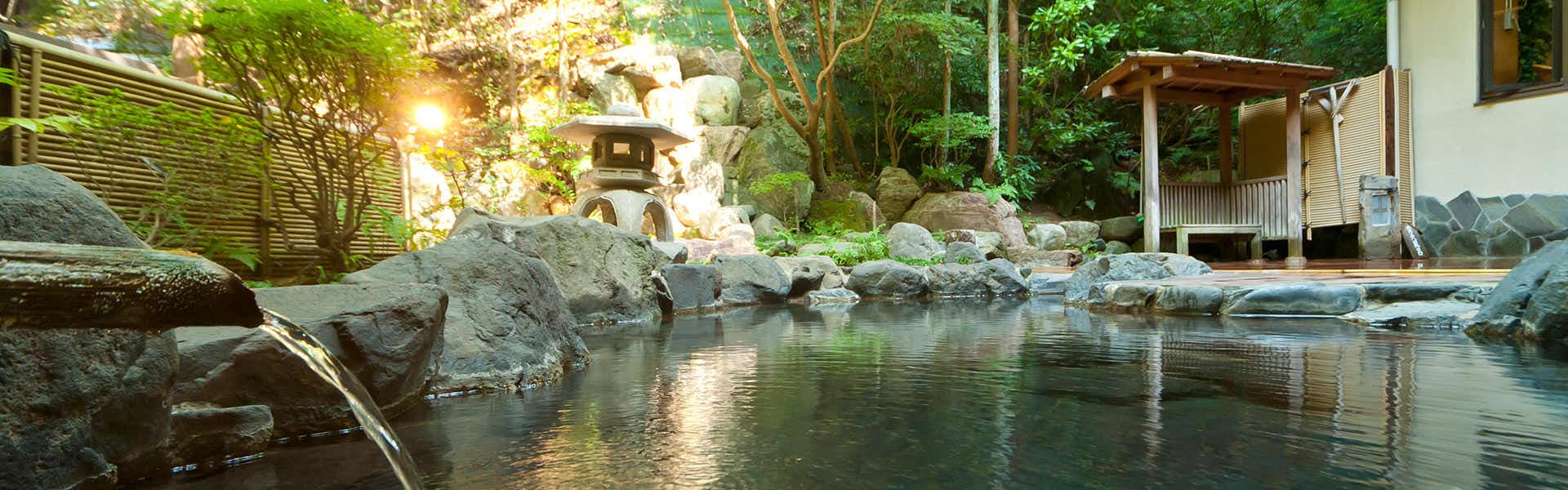 Yamashiro Onsen Yoshidaya Sannoukaku large outdoor rock bath surrounded by dense garden foliage