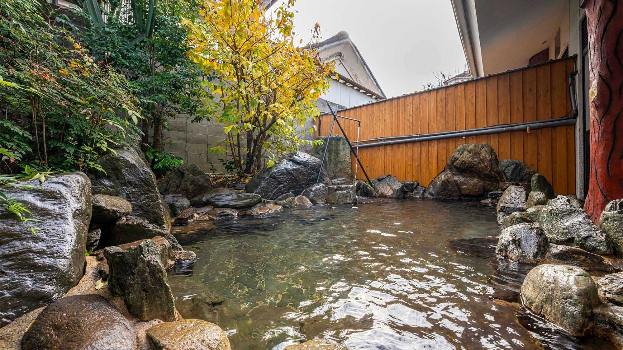 Yamaga Onsen Ryokan Miki with an open-air rock bath enclosed by autumn garden foliage.