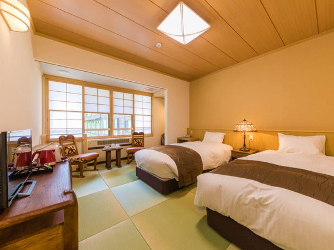 Sukayu Onsen Ryokan with twin beds, tatami flooring, wood furniture, and shoji windows
