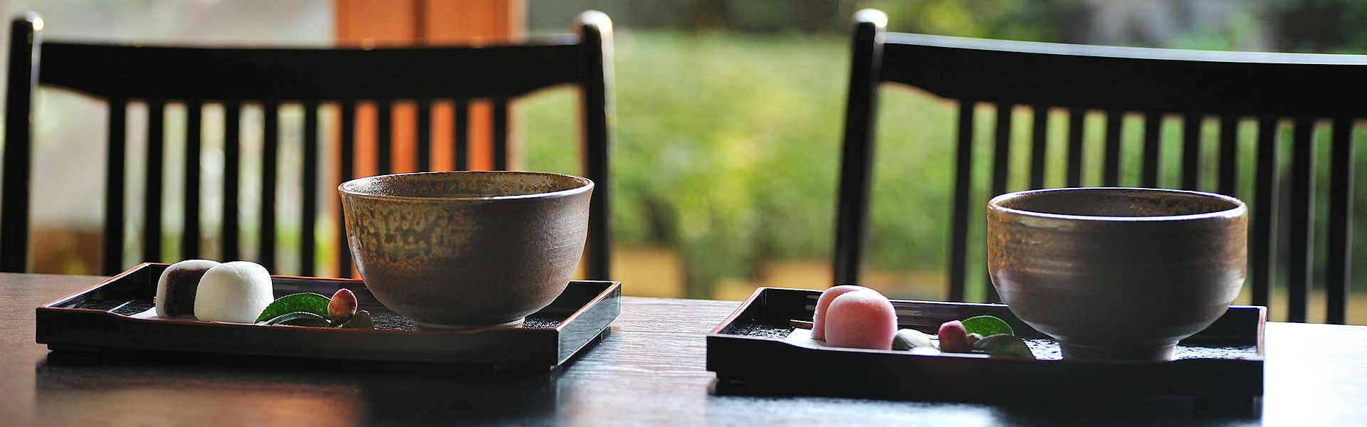 Ibusuki Shusuien Dark ceramic bowl on pedestal stand with black containers beside