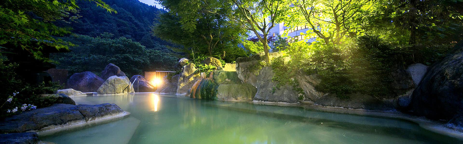 Okuhida Garden Hotel Yakedake with an outdoor bath glowing beneath a deep blue evening sky.