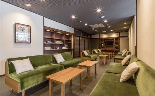 Ryokufuso with a contemporary lounge furnished with green sofas and bookshelves.