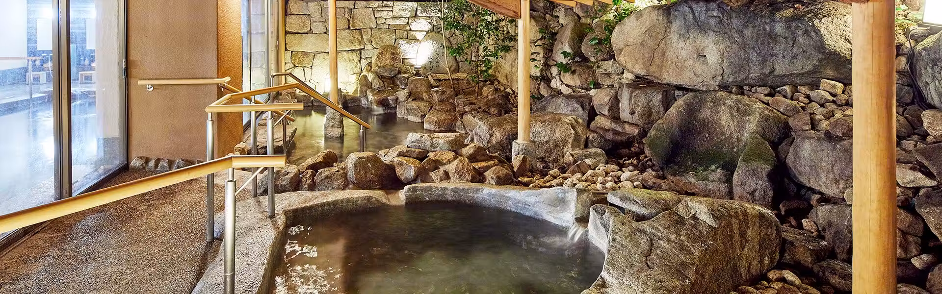 Yamatoya Honten with this scene, where a rock-lined open-air bath faces bamboo screens and a leafy garden.
