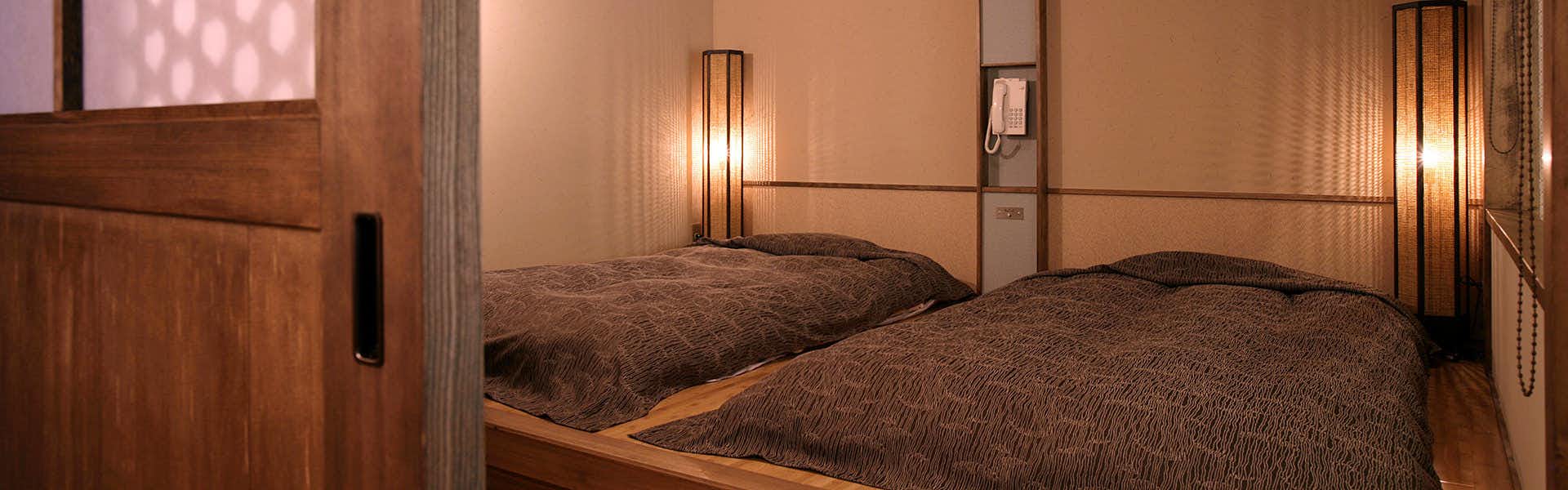 Wado Onsen Yuno Yado Wado with a cozy twin bedroom with warm wall lanterns.