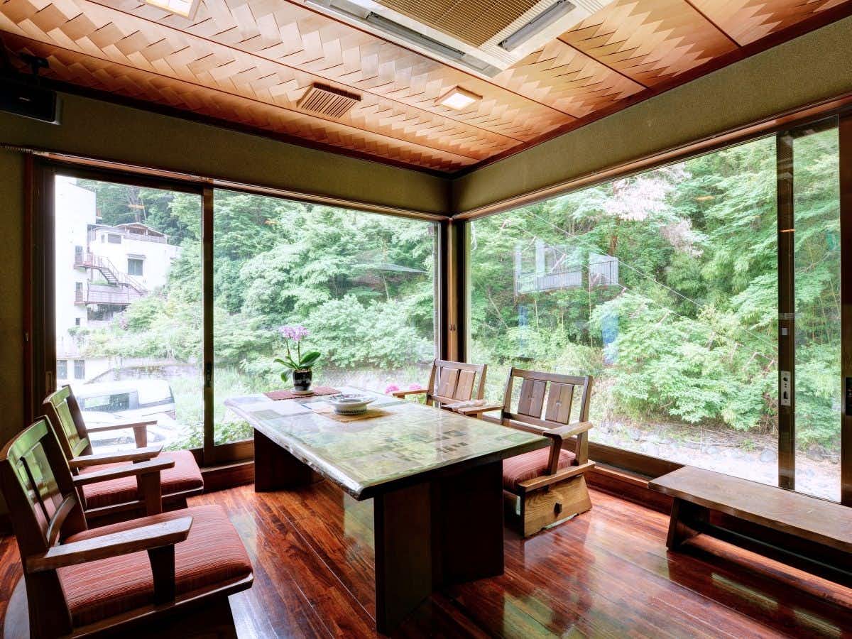 Motoyu Ryokan Daikokuya with a garden-facing dining room with patterned chairs and broad windows.