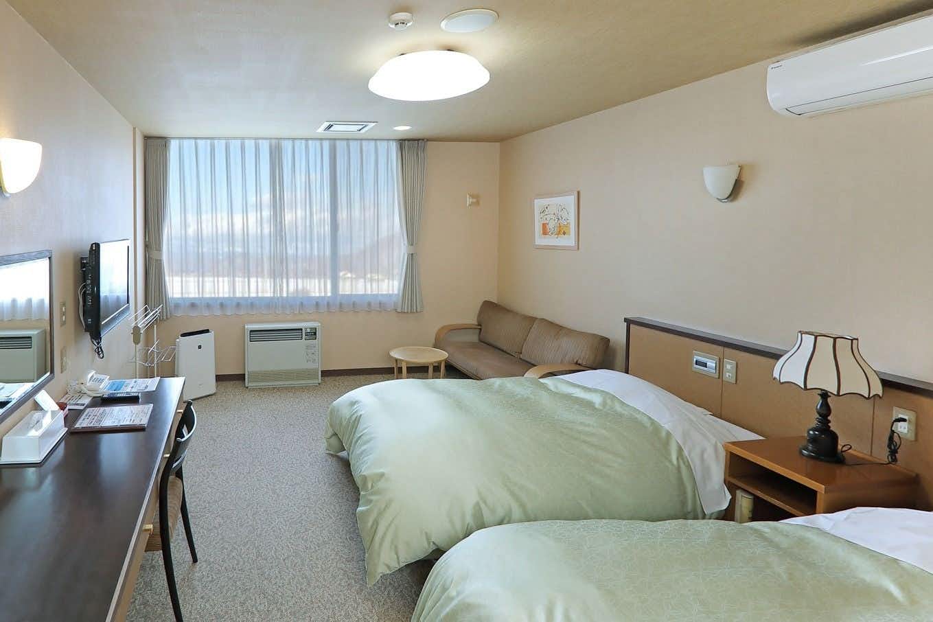 Mitsuishi Kombu Onsen Kurazo with a simple twin bedroom with pale green bedding.