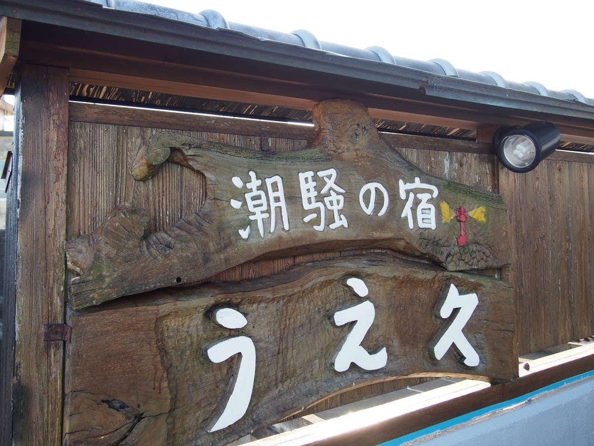 Shiosai no Yado Uehisa with this scene, where a carved wooden sign displays the inn name against the blue sky.