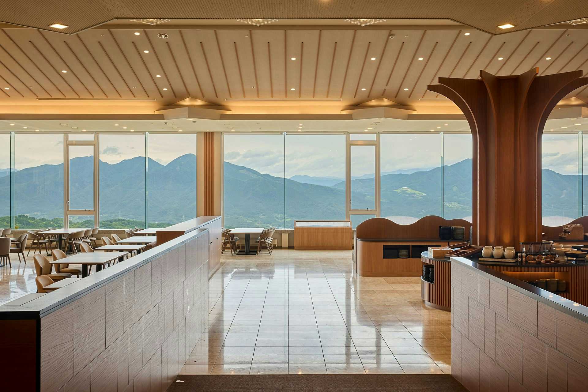 Ikaho Onsen Hotel Kogure with a spacious indoor bath facing layered mountains through floor-to-ceiling windows.