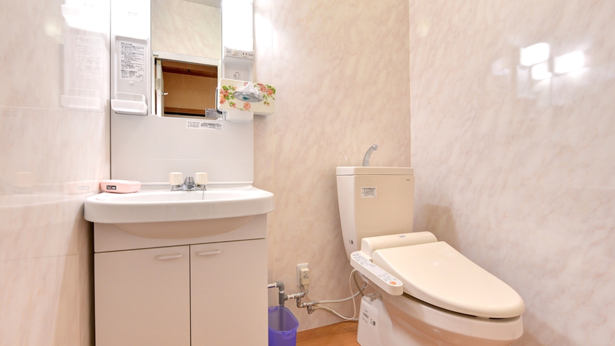 A washbasin and toilet in a bright bathroom.