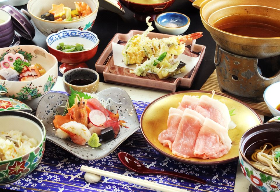 Multi-dish meal with sashimi, vegetables, and soup.