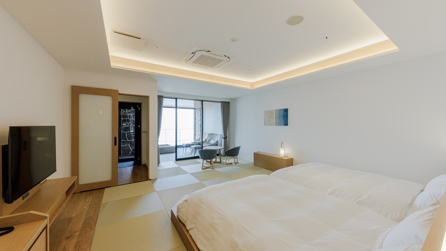 A bright bedroom with twin beds and a sitting area facing the sea.