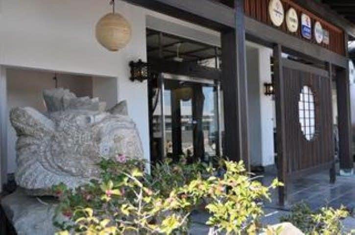Shimanami Kaido Ryokan Fujimien with a sheltered entry courtyard lined with stone carvings and mature trees.
