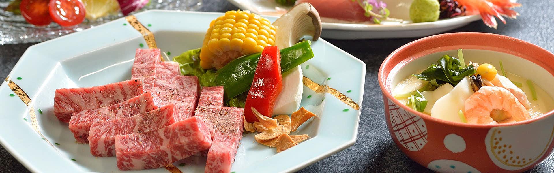 Kaishu with marbled beef cubes served with vegetables on a white plate.