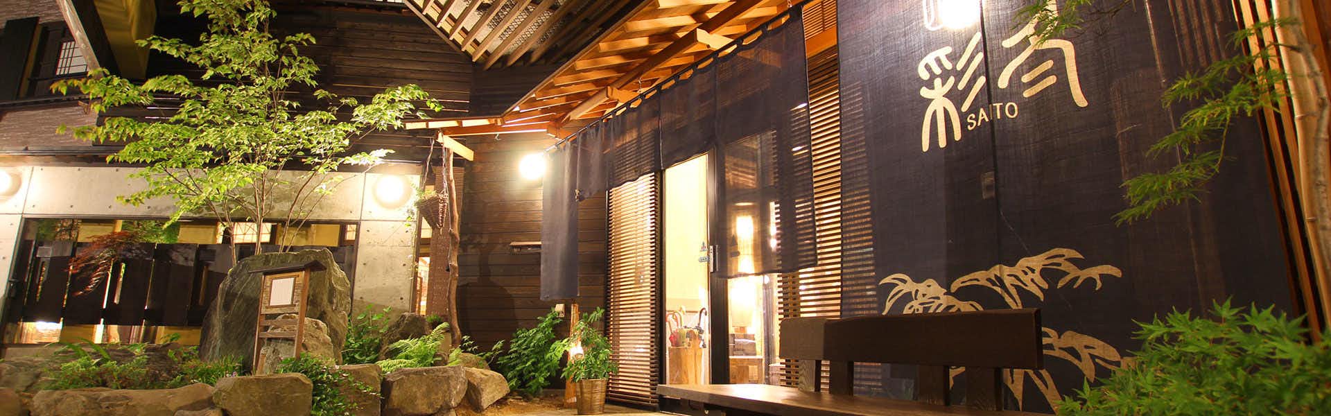Shikikan Saito with a lantern-lit timber entrance surrounded by leafy garden planting.