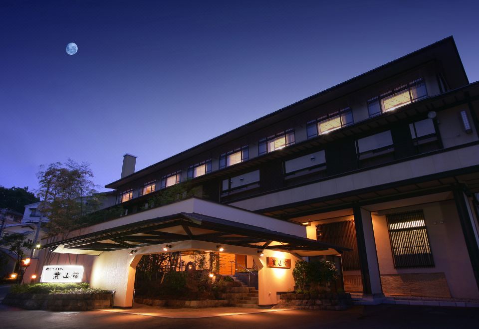 The inn glows beside a mountain view at dusk.