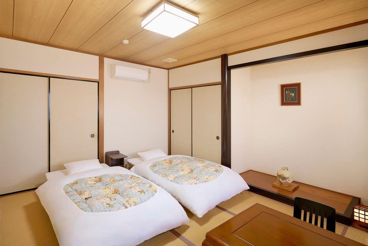 Ryokan Tsukimiso with this scene, where twin futons lie beside a low table in a pale wood-trimmed tatami room.