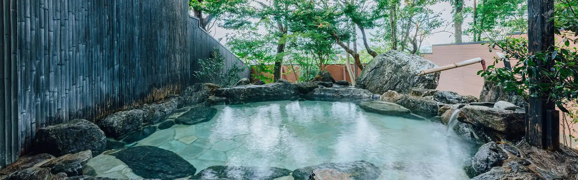 Fukahori-tei with this scene, where its rock-lined outdoor bath rests beneath tall trees.