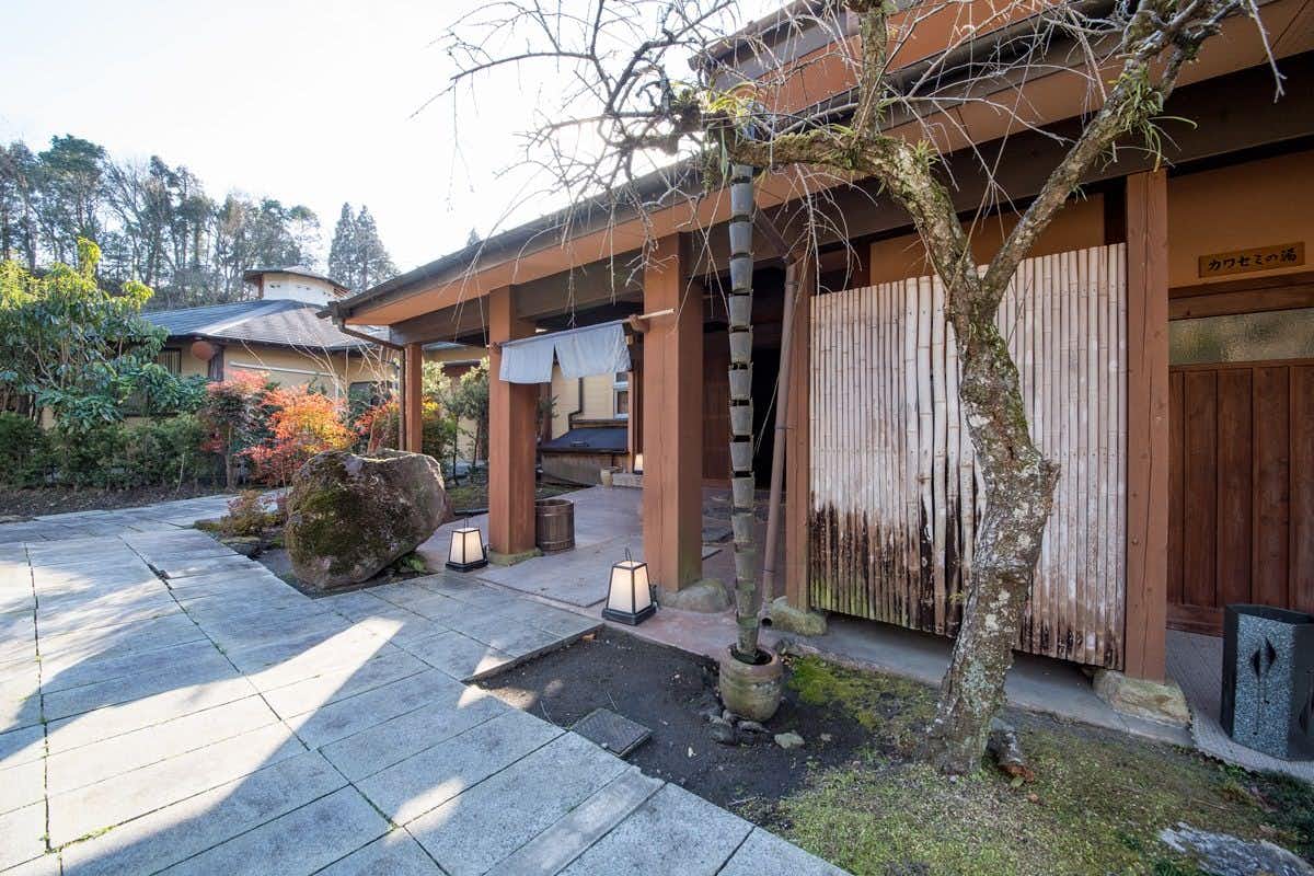 Seasonal Cuisine and Hot Springs Inn Tokiwaso with a quiet entrance path beside timber walls and winter shrubs.