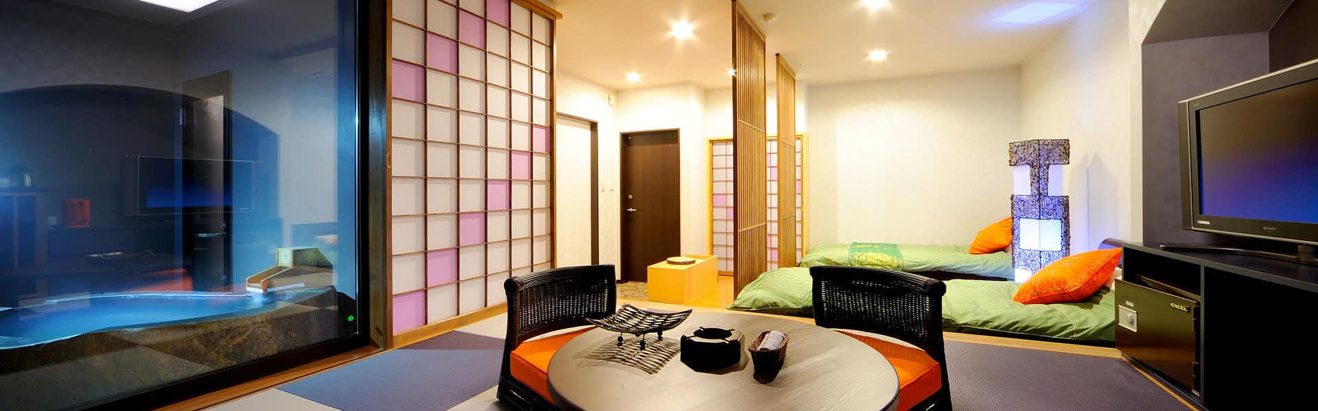 Ryuten Betsutei Kanzan Chogetsu Interior space with geometric pink tiled wall, dark bench seating, orange cushions, and hallway architectural detailing