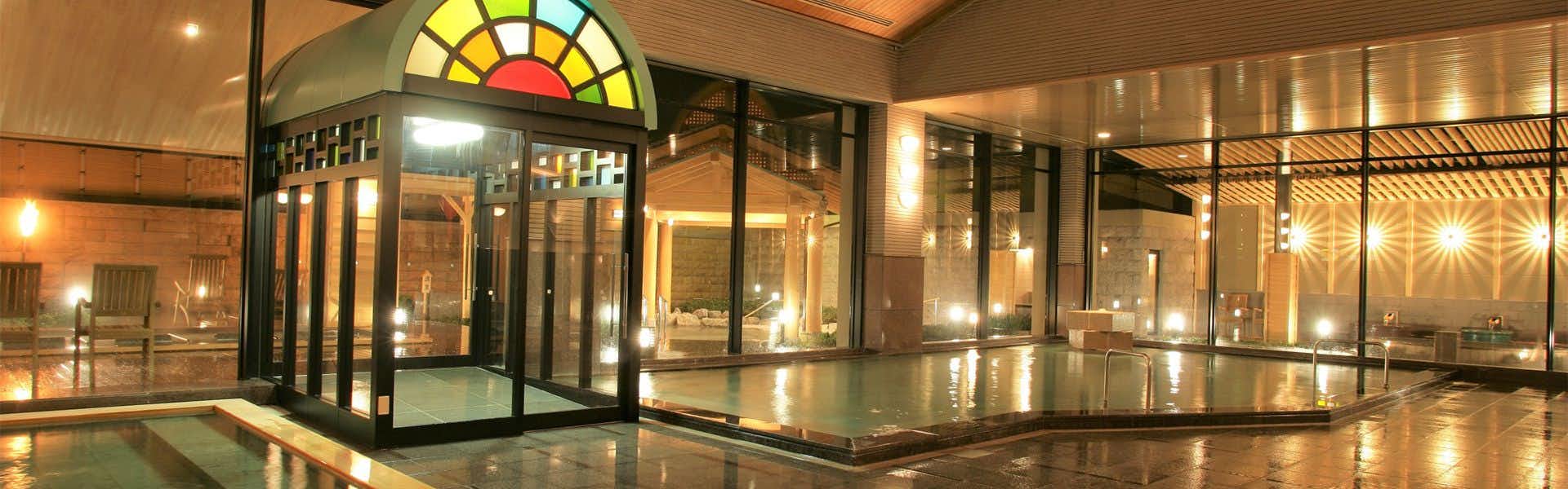 Awara Onsen Matsuyama Sensen with a circular glass entrance reflected across polished stone flooring.