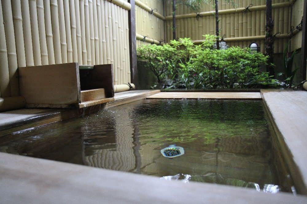 Shotenkyo with a private square soaking bath opening toward garden greenery.