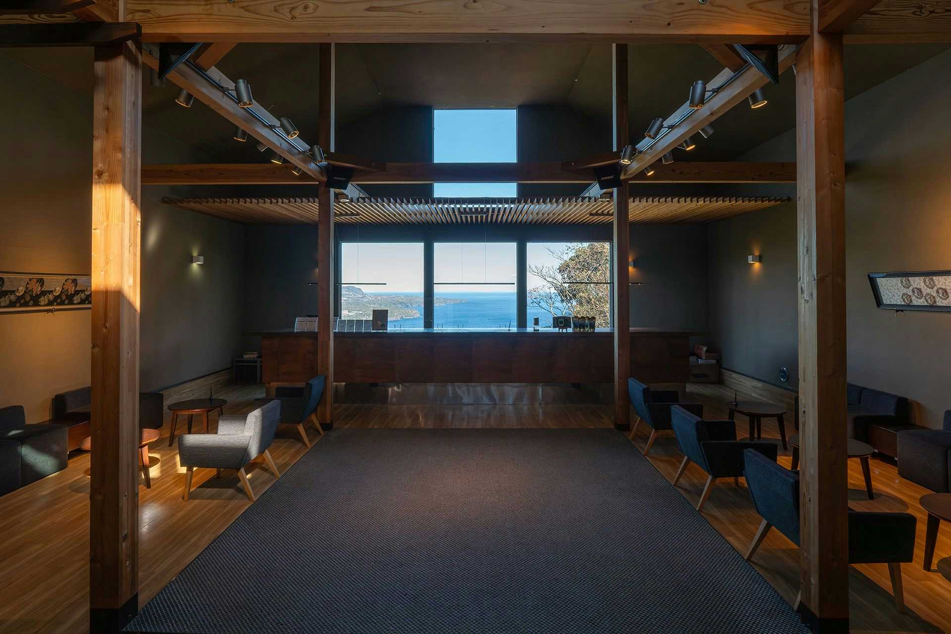Onyado Fuugetsu Muhen with a dark wood lounge framing the sea through broad windows.