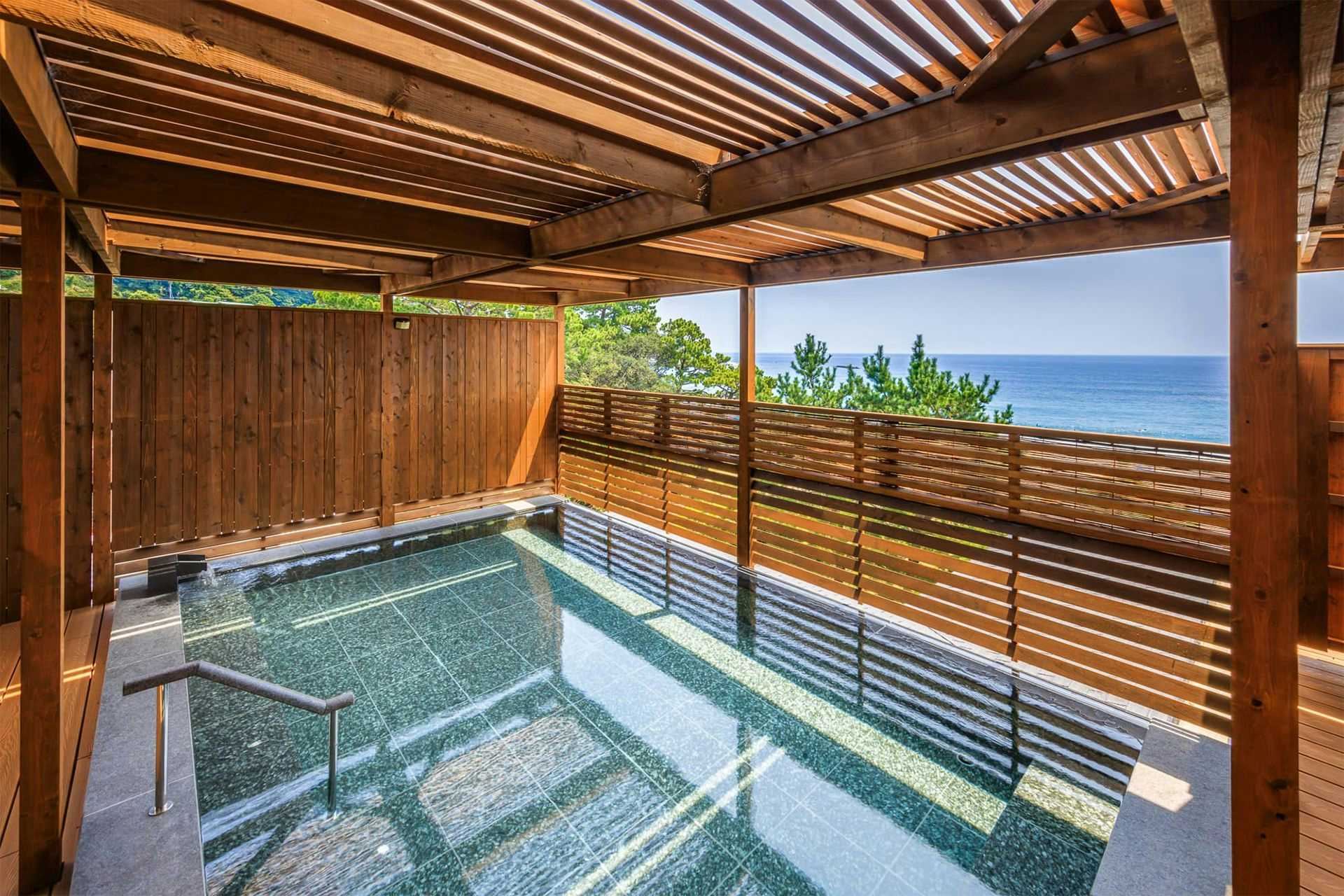 An open-air bath overlooking the bright blue shoreline.