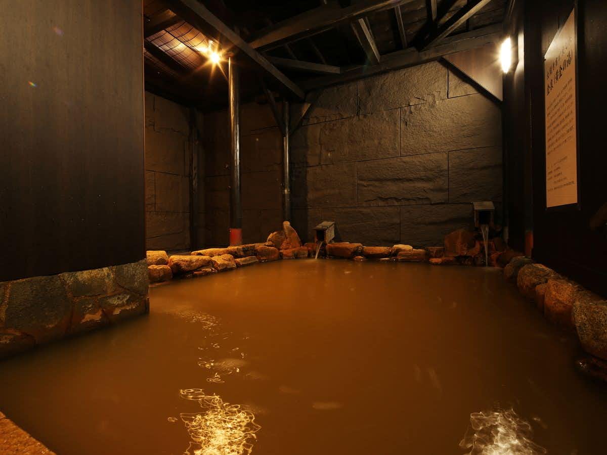 Arima Royal Hotel with a dark rock-lined indoor bath under warm lights.