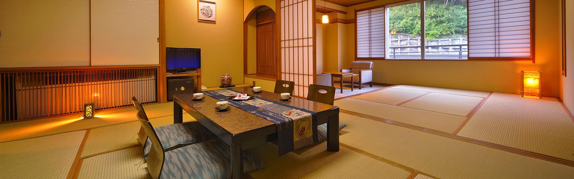 Kamasaki Onsen Suzukiya Ryokan with a spacious tatami room with dark low table and garden window.