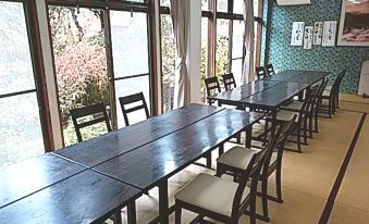 A dining room with tables and chairs beside windows.
