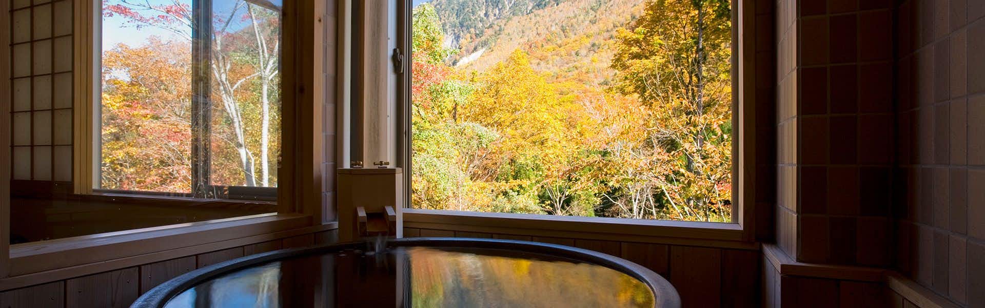 Takumi no Yado Miyama Sakura-an (Kyoritsu Resort) with a private round bath facing vivid autumn foliage through corner windows.