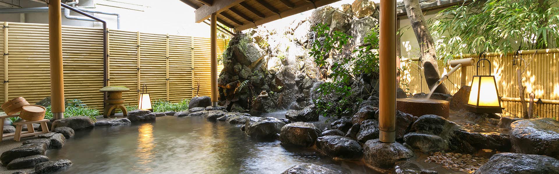 Hakone Yumoto Onsen Kisen-so Outdoor bathing area with stone basin, surrounding rocks, climbing vegetation, wooden support posts, and natural garden setting.