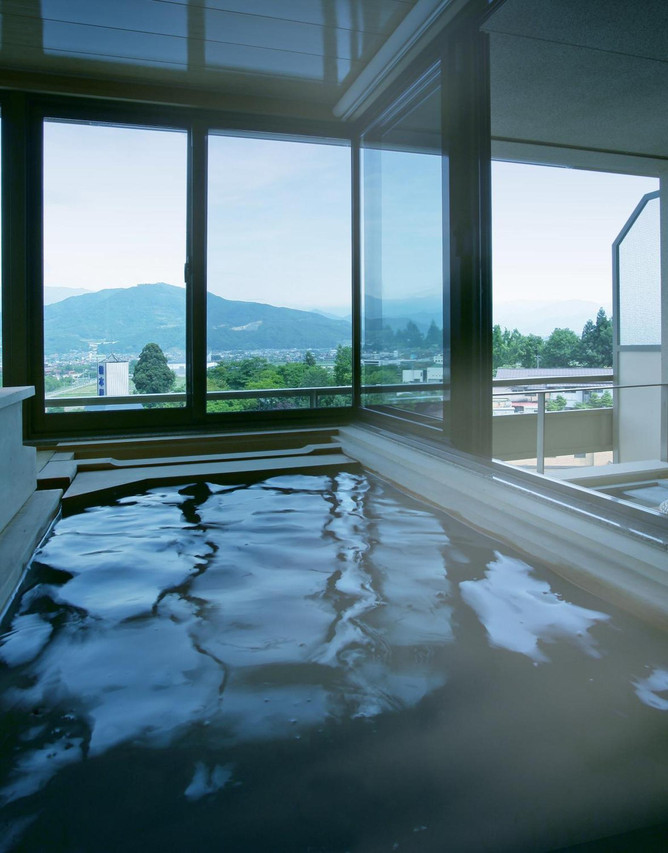 A broad window frames the valley from an indoor bath.