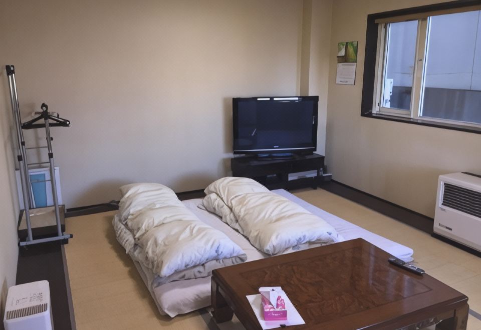 A tatami guest room with two futons, a low table, and a television.