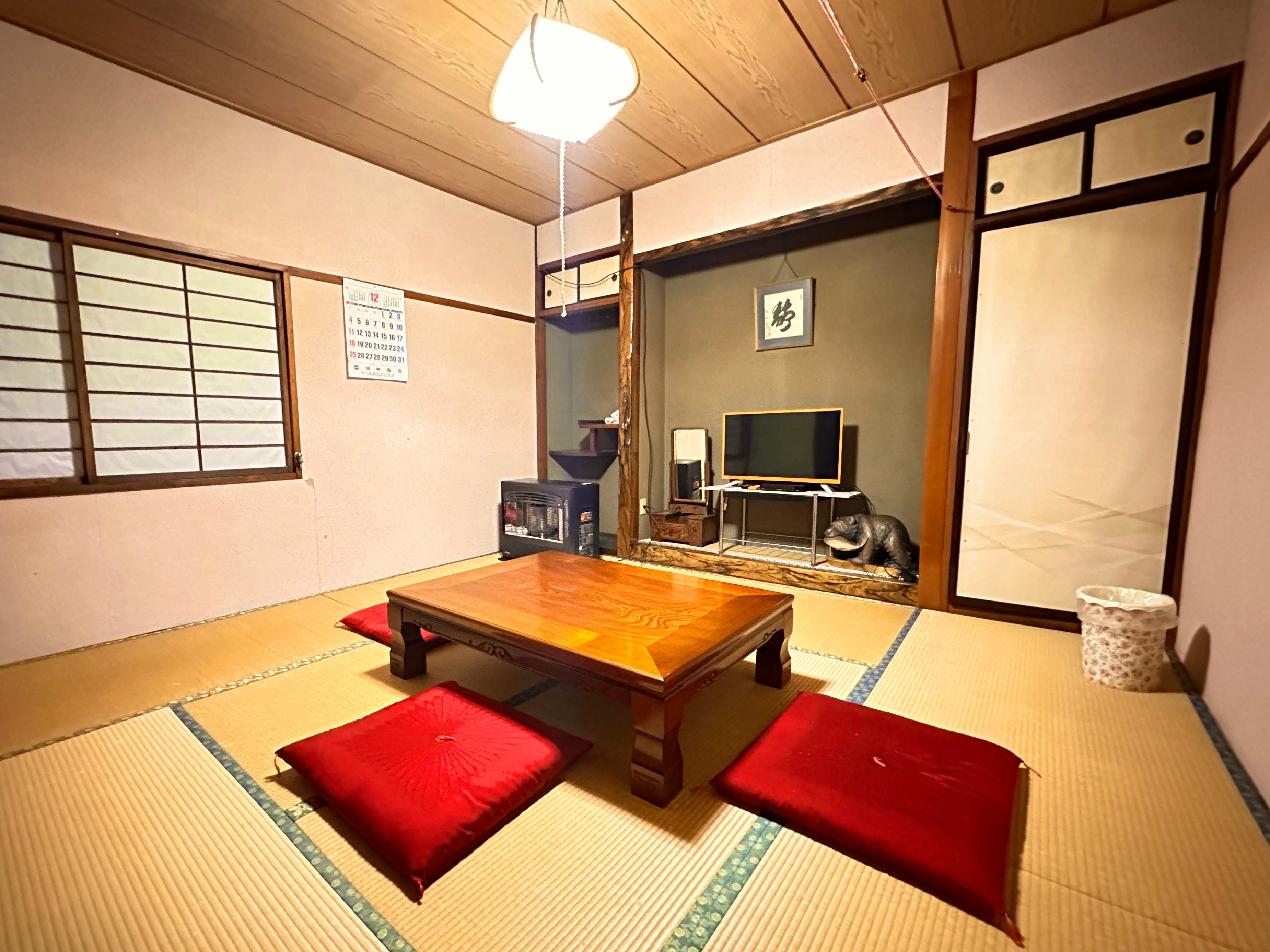 A tatami room with a low table and red cushions.