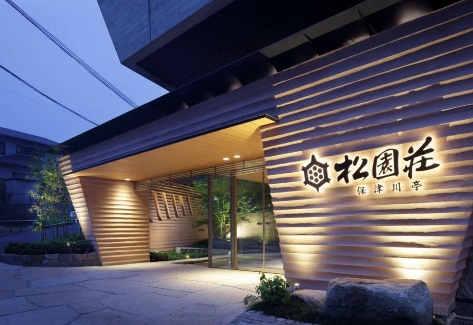 The ryokan entrance with an illuminated Japanese name sign.
