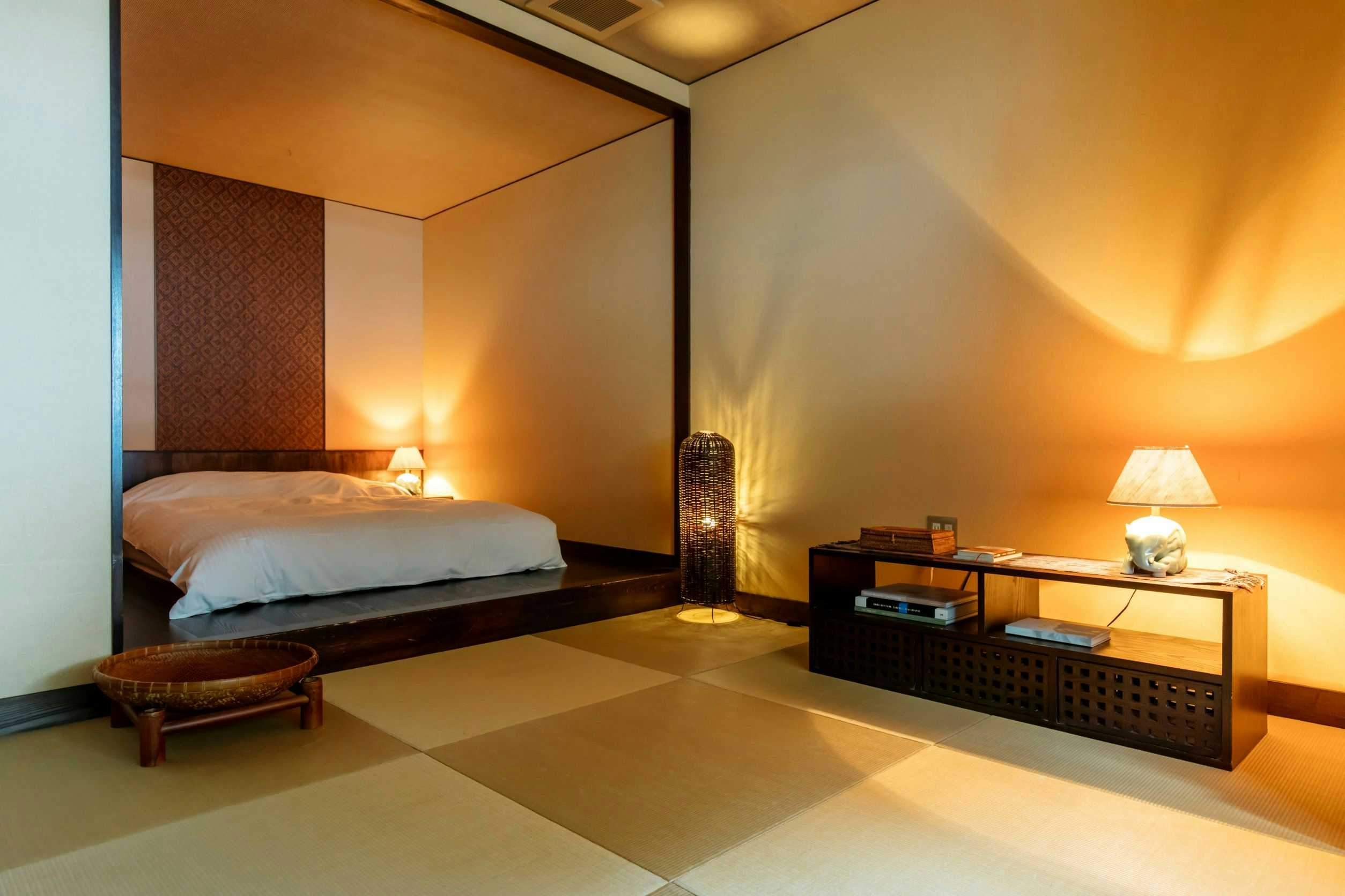 Kinosaki Onsen Sensui Bedroom with white bedding, bedside lamps, wood furniture, and warm wall tones.