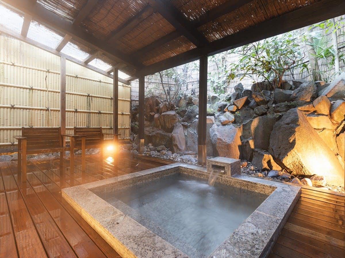 Yushintei with a steaming open-air bath framed by timber beams and rocks.