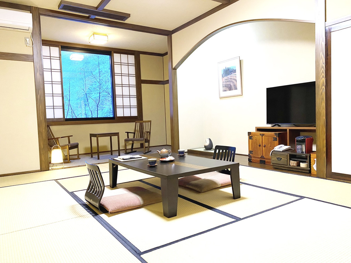 A traditional tatami room has a low table and upholstered floor chairs.