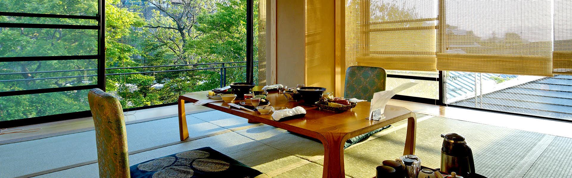Shibu Onsen Shibu Hotel with a window-side dining table overlooking green riverside trees.