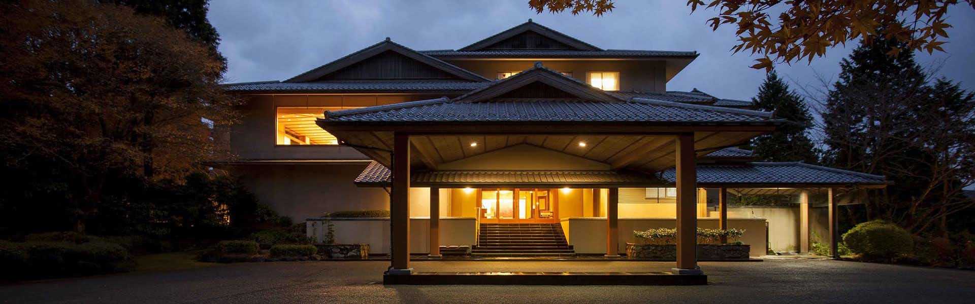 Ryuguden(ryokan) with the illuminated traditional entrance beneath a dark evening sky.