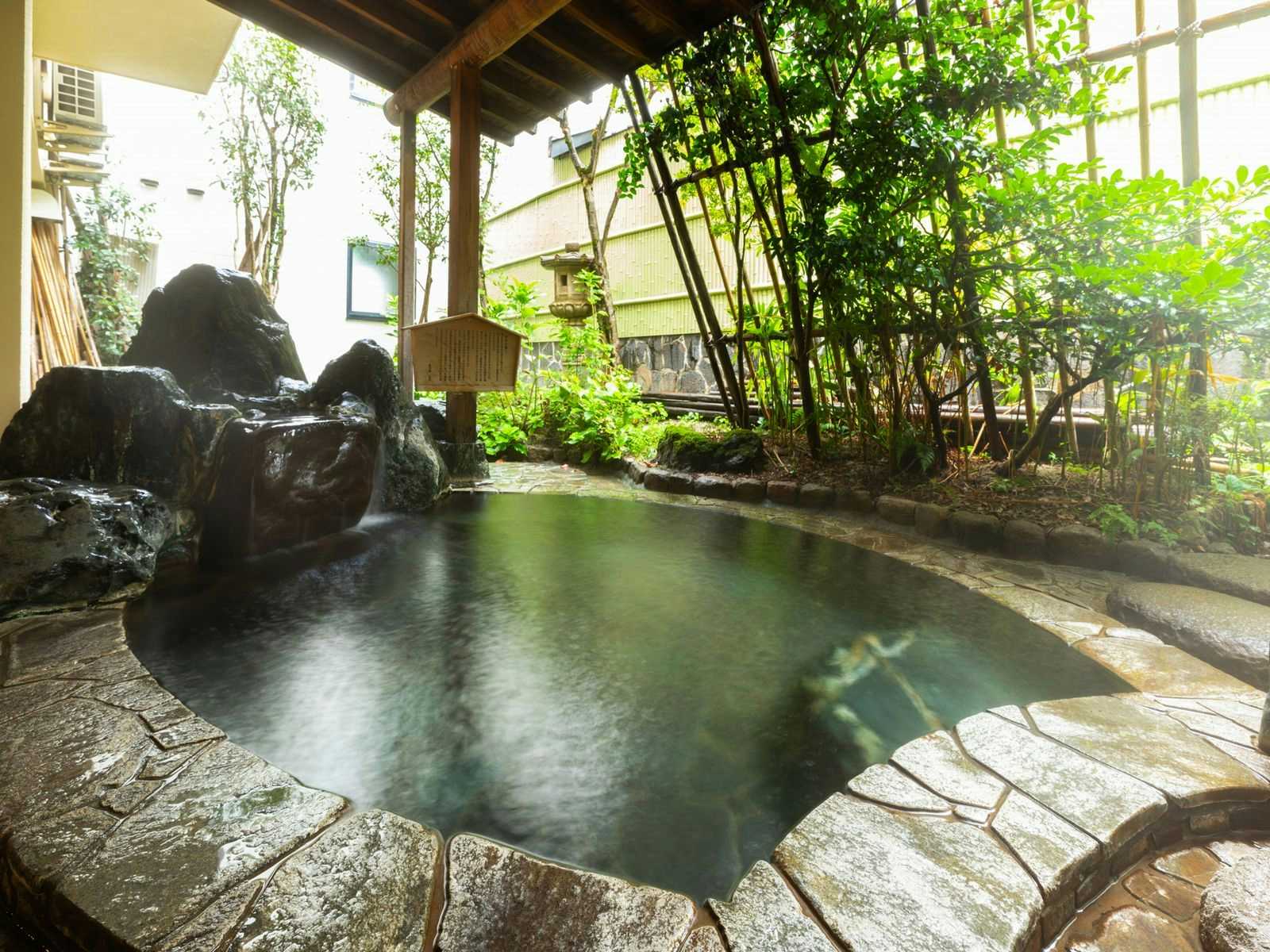 Otowaya Ryokan with an open-air rock bath surrounded by bamboo and garden shrubs.