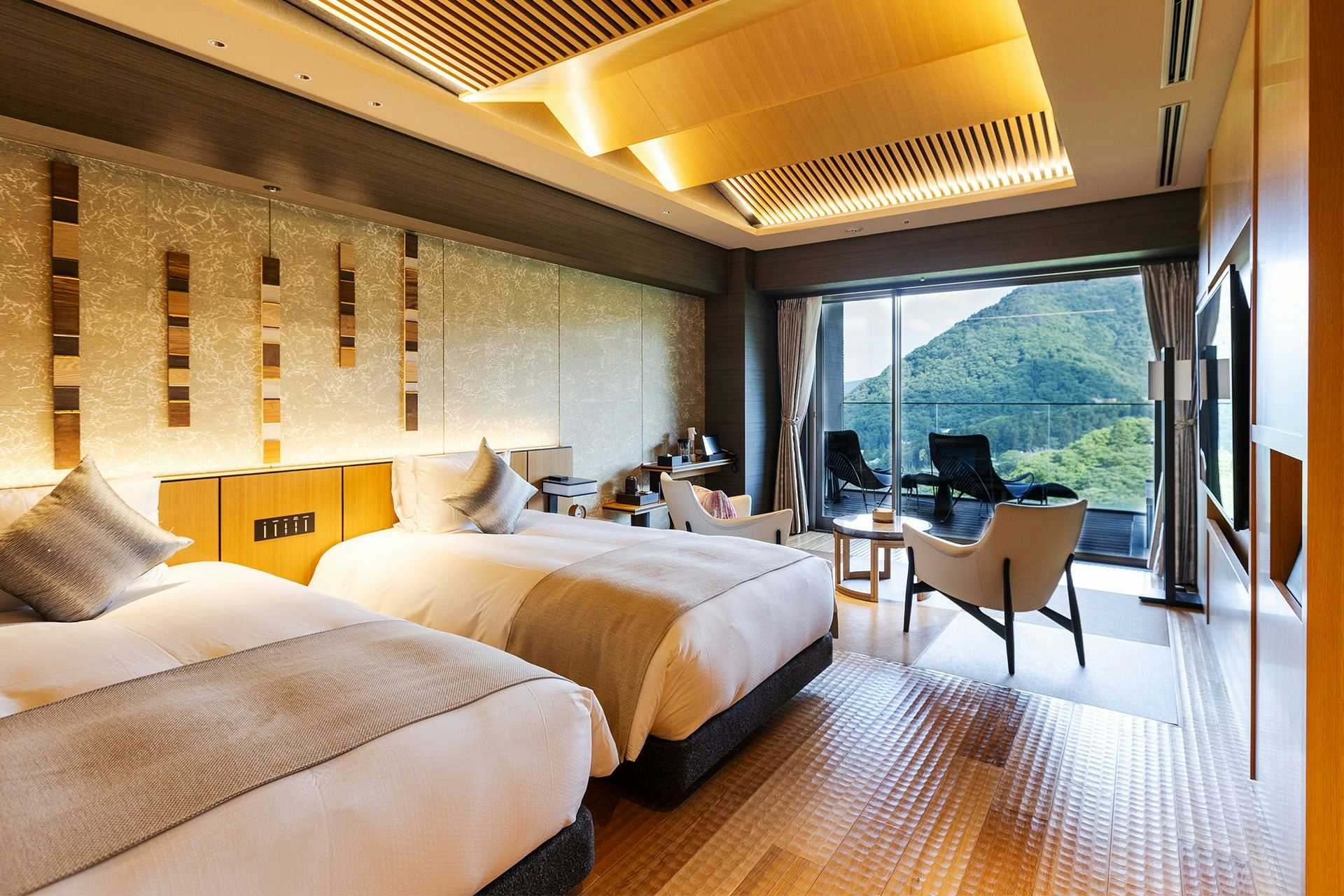 A bright twin bedroom overlooking green mountain ridges.