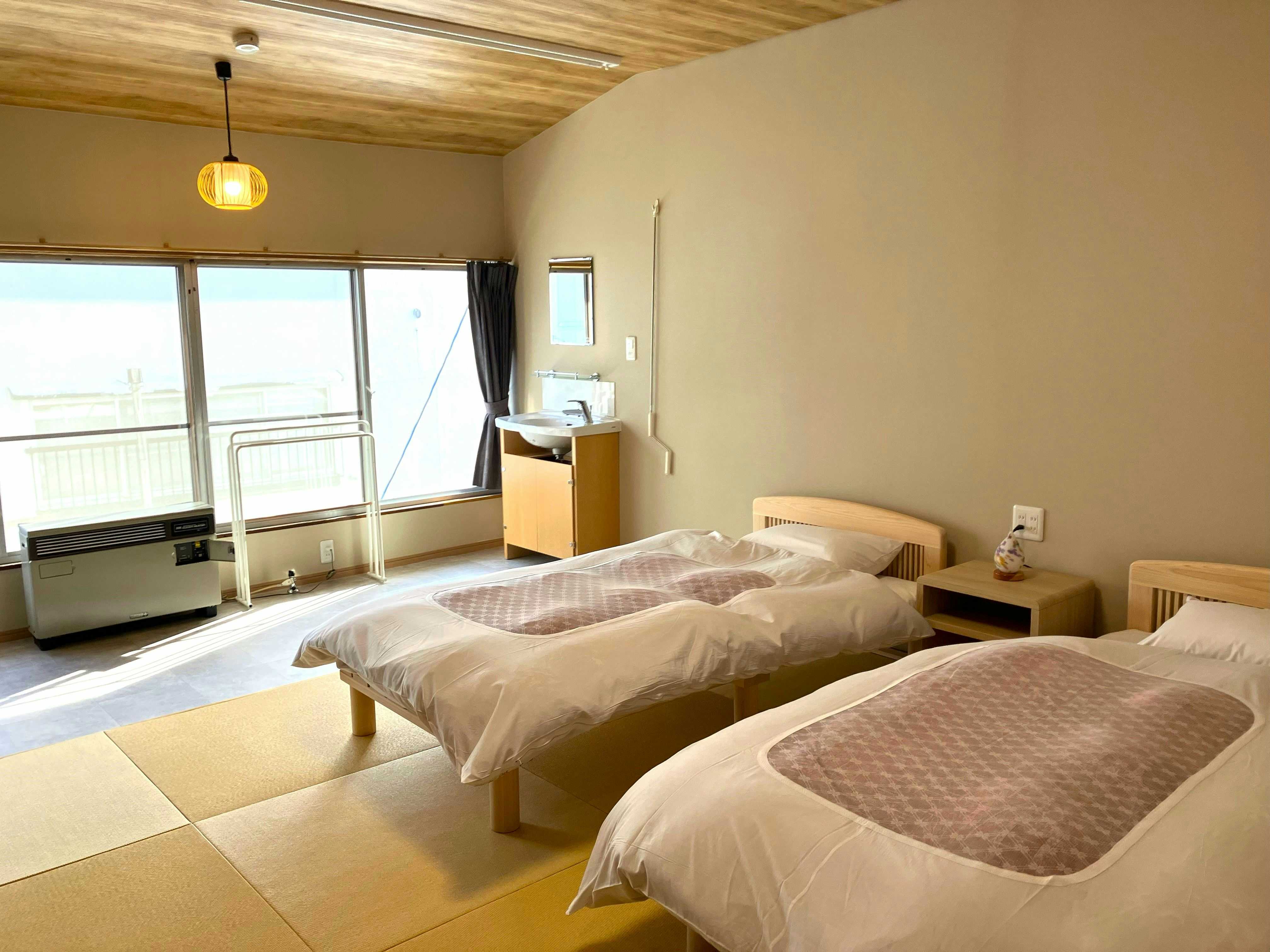 Zao Onsen Takasagoya Ryokan with a bright twin bedroom with simple white bedding.