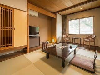 Amakusa Shimoda Onsen Boyokaku with a compact tatami room with wicker chairs beside a bright window.
