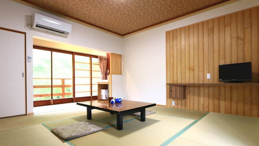 A Japanese guest room with wooden wall panels and a low table beside glass doors.
