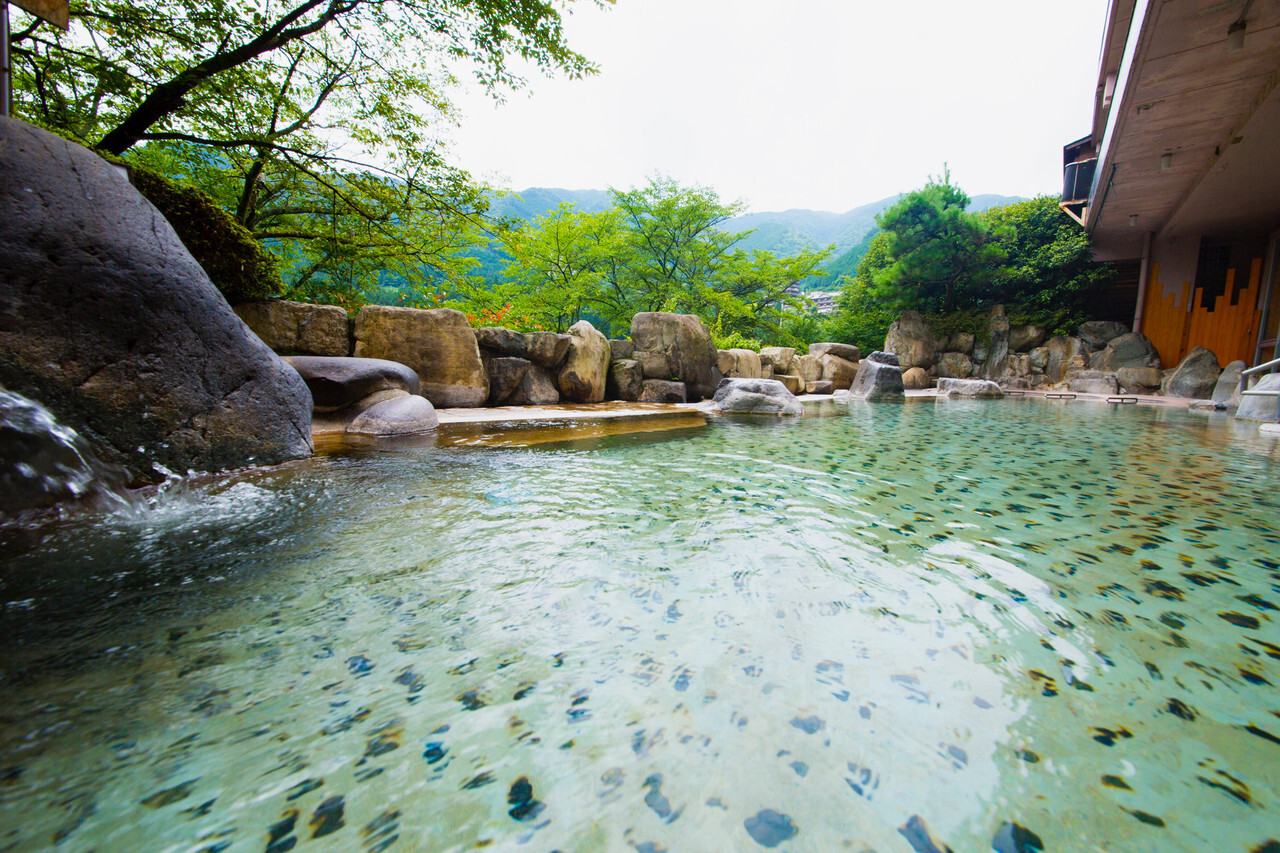 A wide outdoor bath with a mountain backdrop.
