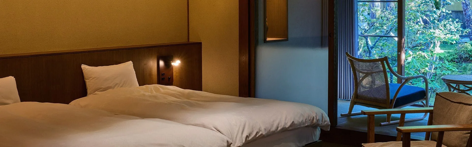 Twin room with warm wood paneling and pine garden view through shoji