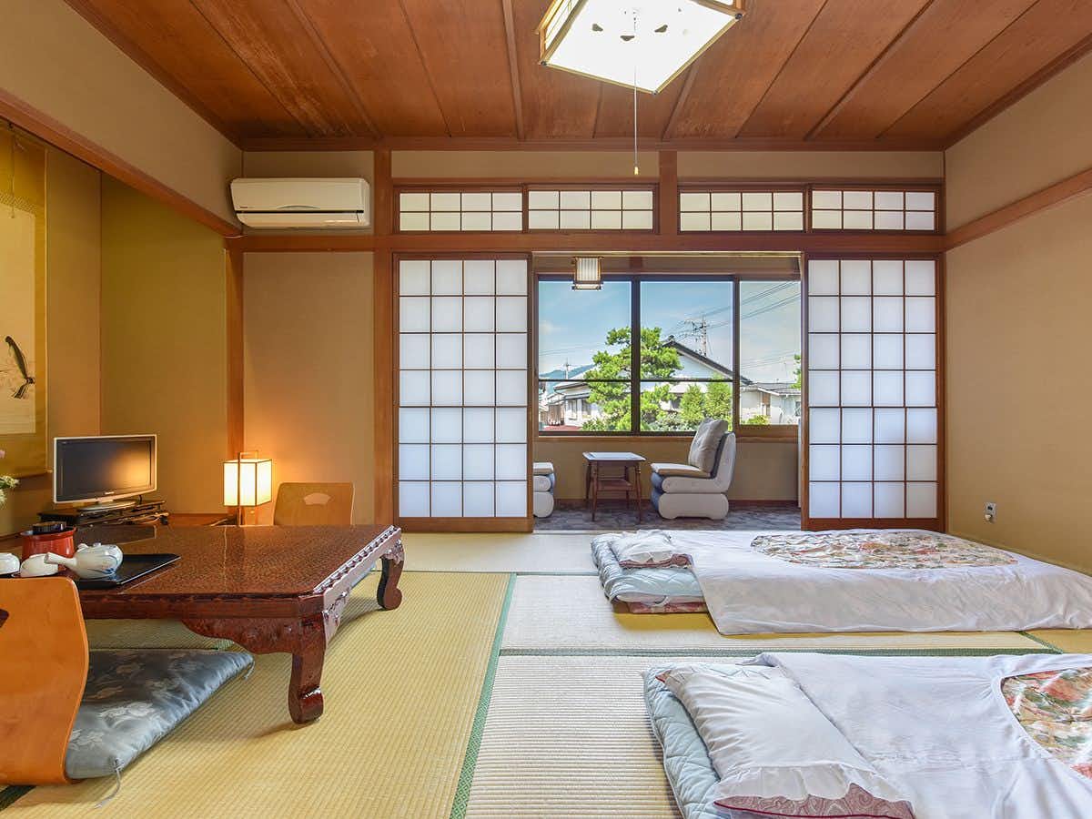 Asahi Ryokan with a spacious tatami sleeping room with futons and a low table.