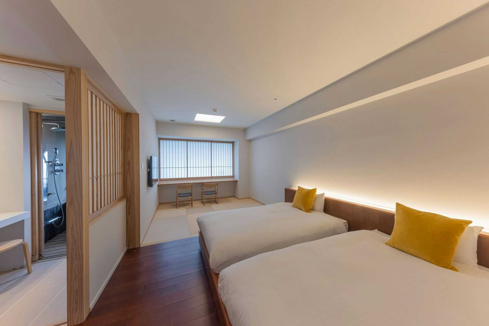 Obama Onsen Iseya with this scene, where twin beds anchor a spacious pale room with a long timber floor.